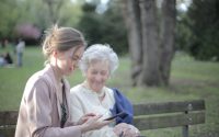 daughter explaining elderly mother how using smartphone