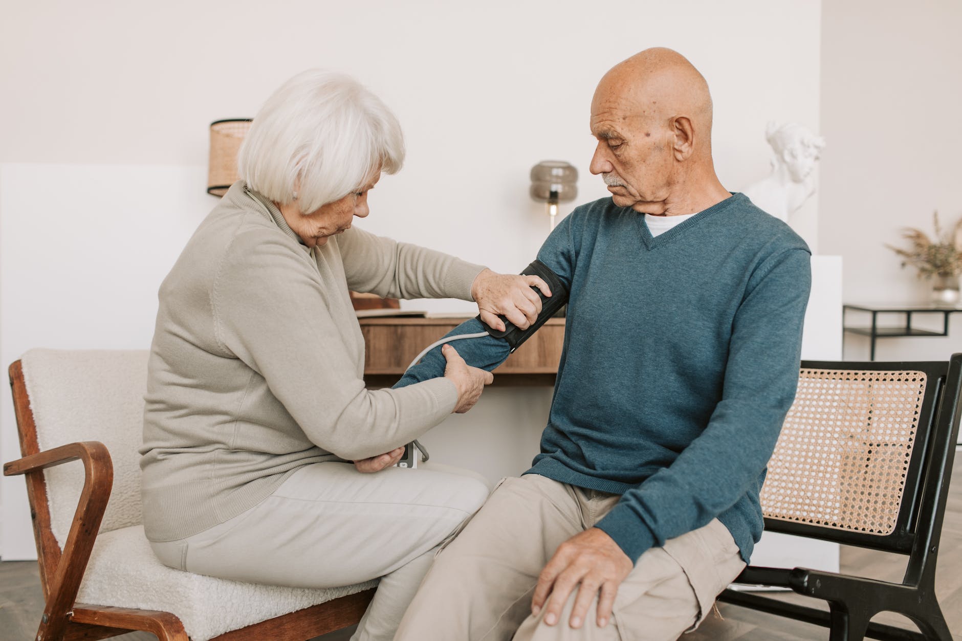elderly woman checking the blood pressure of an elderly man