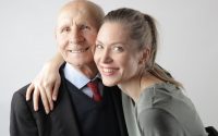 delighted senior father and adult daughter hugging in studio